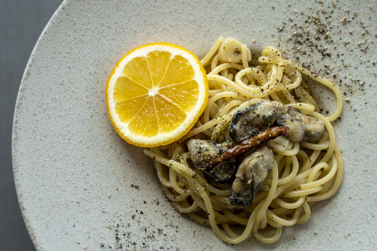 長崎県産牡蠣のペペロンチーノとレモンスライスが盛り付けられた皿