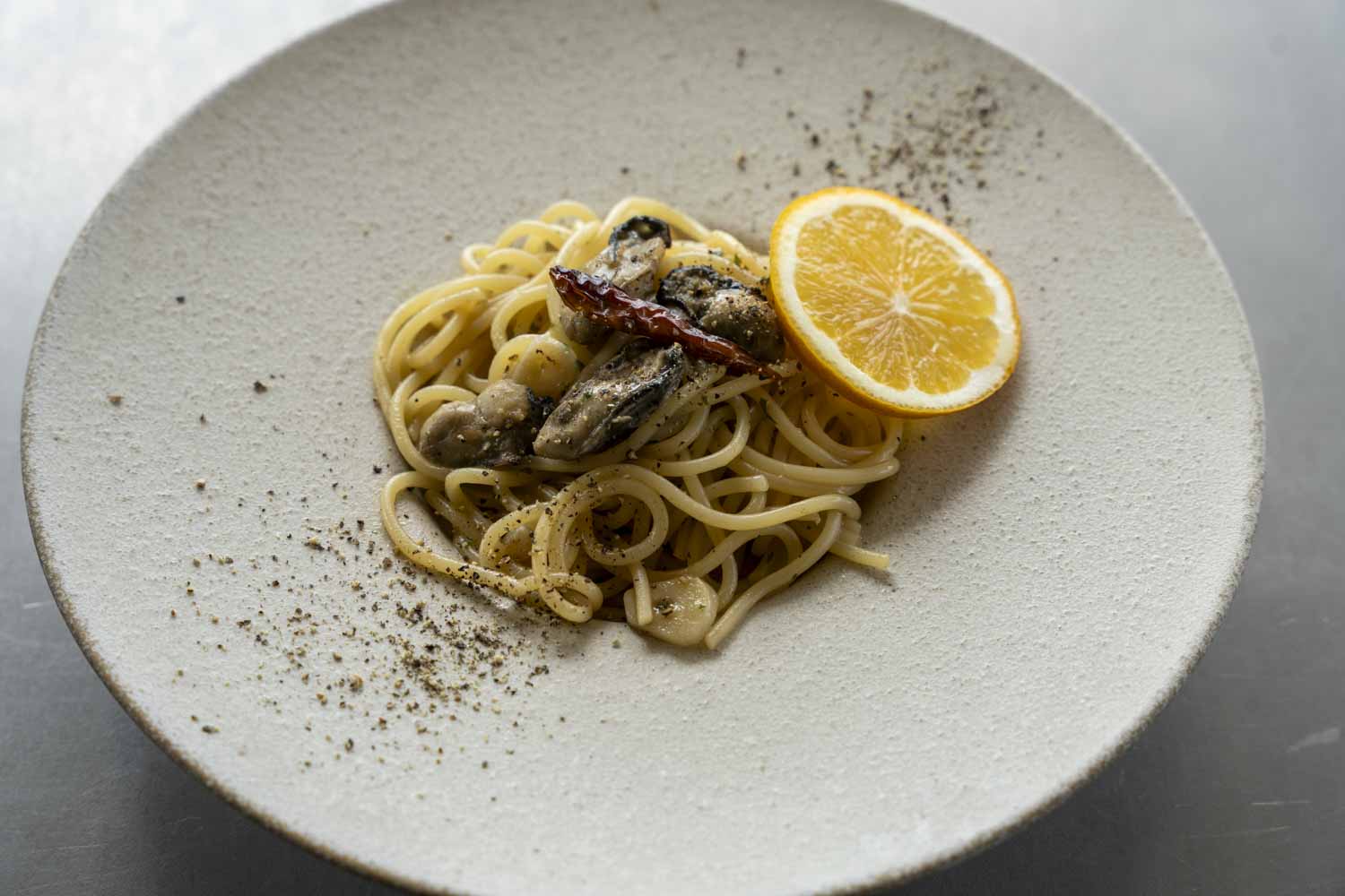 長崎県産牡蠣のペペロンチーノとレモンスライスが盛り付けられた皿