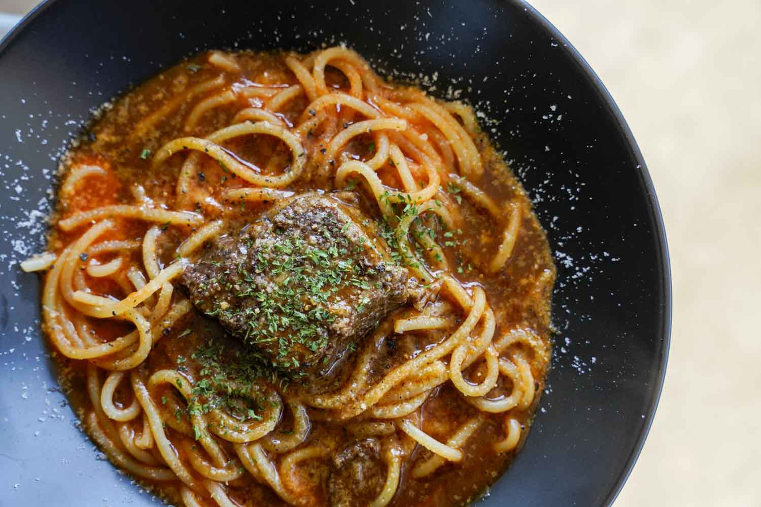 牛スネ肉のトロトロ煮を乗せた濃厚トマトソースパスタのアップ写真